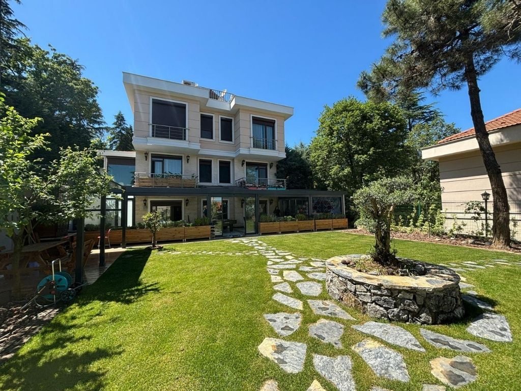 Villa bahçesinden görülen uzun camlı kış bahçesi ve ağaçlar