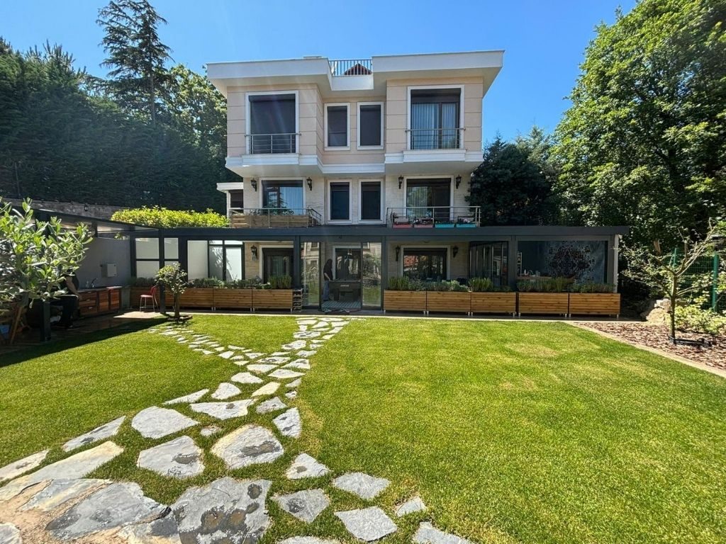 Çim bahçe ve taş yürüyüş yolunun arkasındaki villa kış bahçesi
